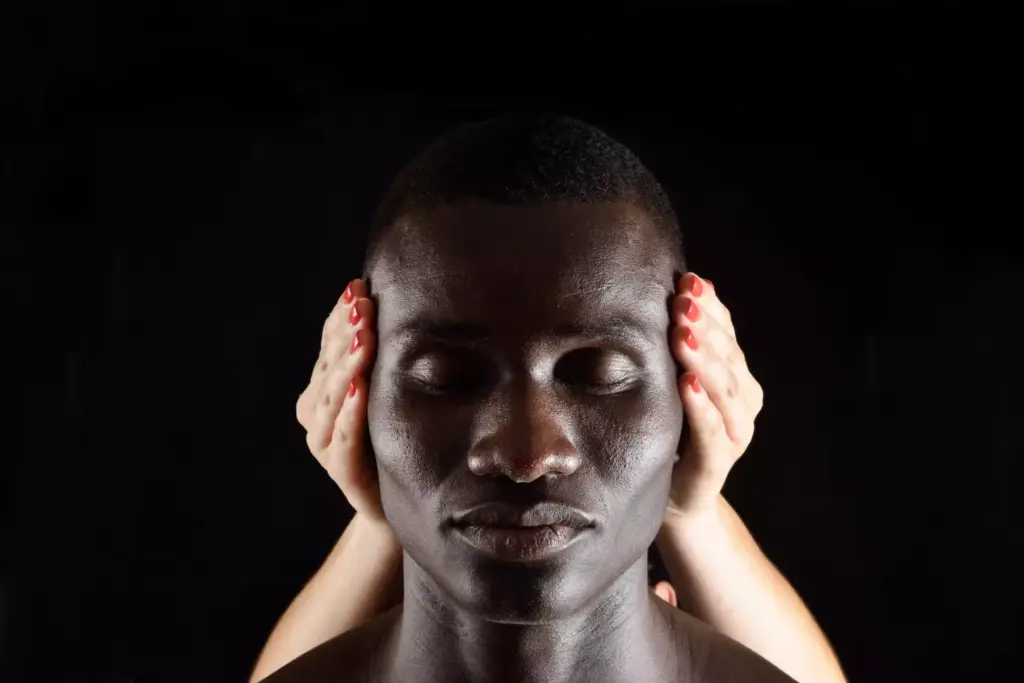 A close-up of a human head, with a pained expression on the face and hands grasping the temples. The lighting is dramatic, with harsh shadows casting a sense of intensity and discomfort. The background is a blurred, muted palette, keeping the focus solely on the intense, throbbing headache being experienced. The lens is slightly wider than a standard portrait, capturing the full anguish of the subject. The mood is one of distress and unease, conveying the persistent, unrelenting nature of the headache.