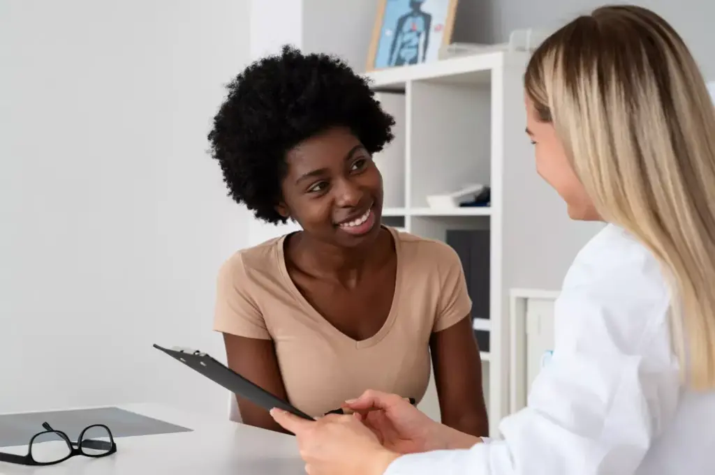 A compassionate woman offers financial guidance and support to a breast cancer patient, sitting together in a cozy, well-lit office. Warm lighting illuminates their faces as they review paperwork, discussing options for medical expenses and treatment costs. The background is softly blurred, focusing attention on their collaborative, empathetic interaction. The scene conveys a sense of care, understanding, and the vital importance of financial assistance during the difficult breast cancer journey.