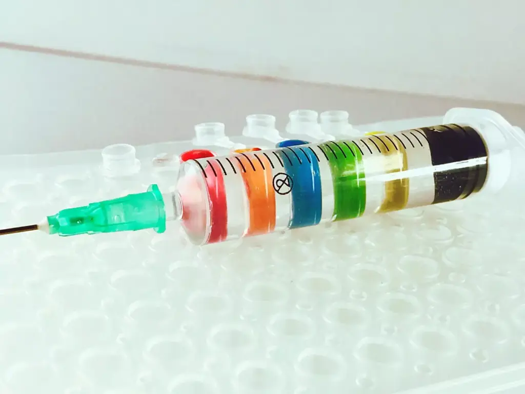 A detailed close-up view of a syringe filled with chemotherapy medication, resting atop an array of medical equipment and supplies. The syringe is centered in the frame, capturing the translucent amber liquid and the intricate needle. The background is a softly blurred hospital environment, with the faint outlines of IV stands, tubing, and other treatment paraphernalia. The lighting is clinical and precise, casting a cool, sterile ambiance. The composition emphasizes the significance and gravity of the TC chemotherapy regimen for breast cancer patients, conveying a sense of the care and precision required in its administration.