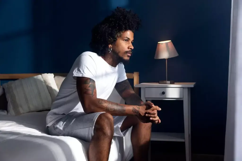 A dimly lit room with soft, warm lighting. In the foreground, a person sits on the edge of a bed, their hands resting on their lap as they prepare mentally for the upcoming chemotherapy session. The middle ground shows a bedside table with a glass of water, a notebook, and a few personal items. The background blurs out, creating a sense of focus and contemplation. The person's expression is one of determination, with a hint of apprehension, as they mentally steel themselves for the challenges ahead. The overall tone is one of quiet reflection and a sense of facing the unknown with courage.