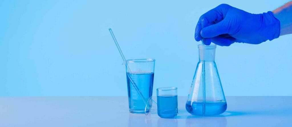 A glass laboratory beaker filled with a vibrant blue liquid, representing chemotherapy drugs for pancreatic cancer treatment