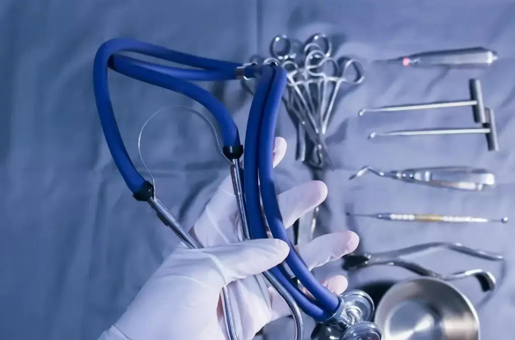 A high-quality, sharply focused image of a selection of modern laparoscopic surgical instruments arranged neatly on a dimly lit metal surface. The instruments include a laparoscope, grasping forceps, scissors, and other essential tools used in minimally invasive procedures. The lighting is dramatic, creating deep shadows and highlights that emphasize the sleek, precise design of the instruments. The composition places the tools in the foreground against a plain, dark background, allowing them to be the sole focus of the image. The overall mood is one of clinical professionalism and technological advancement, reflecting the evolution of laparoscopic techniques.