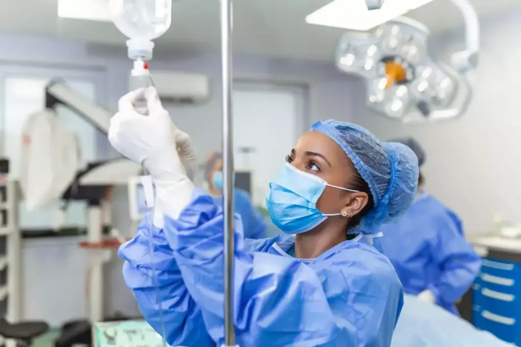 A sterile, brightly lit hospital room with a chemotherapy IV infusion setup in the foreground. A clear plastic IV bag filled with a chemotherapeutic agent hangs from a metal stand, its tubing snaking down to a patient's arm, secured with medical tape. The patient's hand rests on crisp white bedsheets, the arm partially obscured by a medical gown. The middle ground features various medical equipment and monitors, their displays providing vital data. In the background, a large window overlooks a peaceful, urban landscape, the city skyline visible in the distance. The atmosphere is one of calm professionalism, the scene conveying the intricate science and technology behind oncology infusion therapy.
