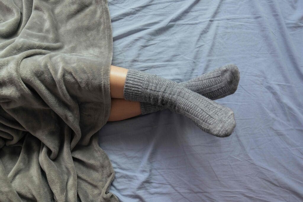 Compression socks in a crisp, clean white, lying against a pale blue bed sheet.