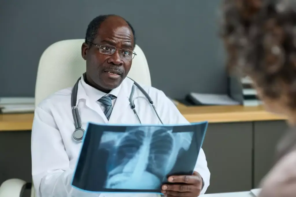 Confident experienced radiologist with lung xray talking to female patient Confident experienced radiologist with lung xray talking to female patient