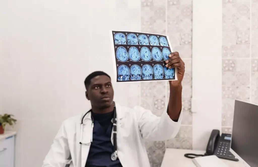 High-contrast medical MRI image of a human brain, clearly displaying a large, irregularly-shaped tumor in the frontal lobe. The scan is rendered in grayscale with a subtle blue-green hue, conveying a clinical, analytical atmosphere. The brain is sharply in focus, surrounded by a softly blurred background that suggests the sterile environment of a medical imaging lab. Precise anatomical details are visible, showcasing the complexity and value of brain tumor MRI datasets for advanced medical research and analysis.